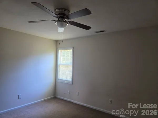 an empty room with a window and a fan