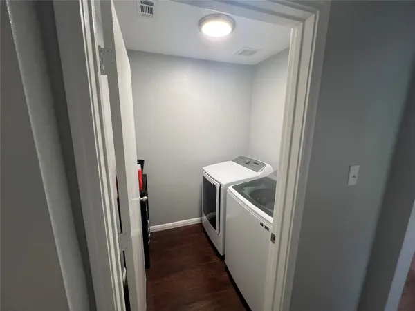 a utility room with wooden floor washer and dryer