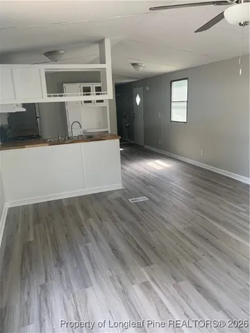 a living room with hard wood floors and kitchen view