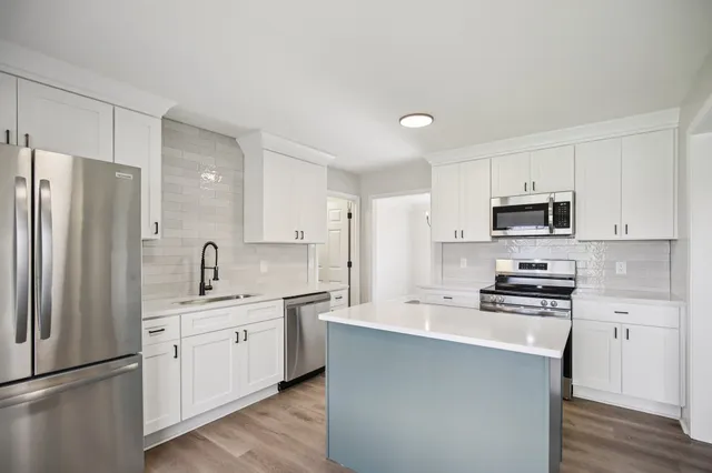 a kitchen with white cabinets and stainless steel appliances