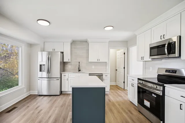 a kitchen with white cabinets and stainless steel appliances