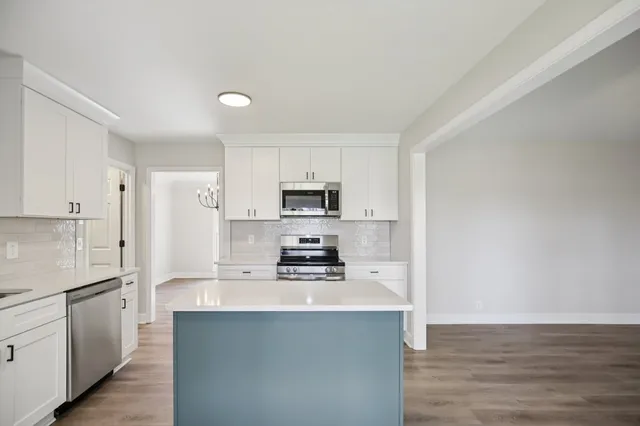 a kitchen with stainless steel appliances a stove a sink a refrigerator a microwave and cabinets