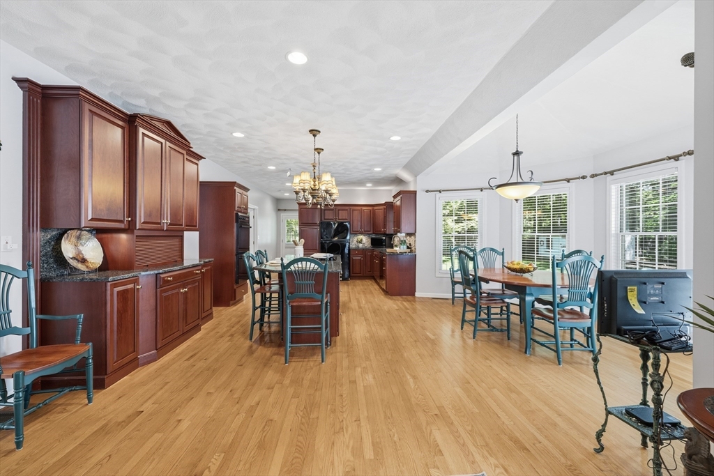 25 Haymeadow Road Boxford, MA 01921 - Photo 15 of 42 a dining hall with stainless steel appliances granite countertop a stove a refrigerator a dining table and chairs with wooden floor