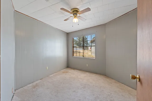 an empty room with windows and ceiling fan