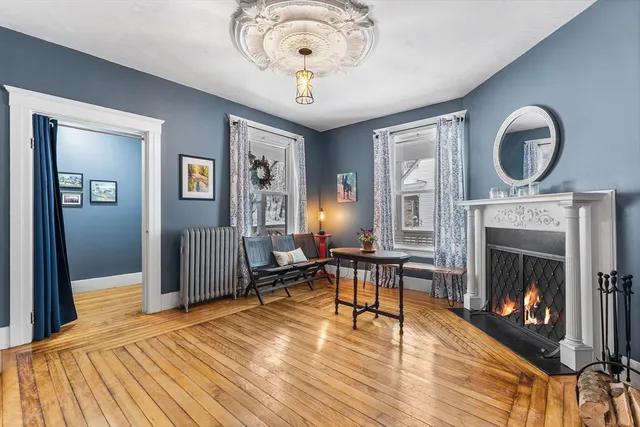 a view of a livingroom with furniture a fireplace wooden floor and a chandelier