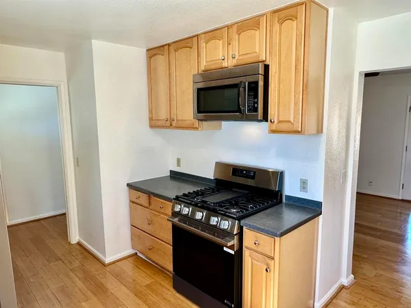 a kitchen with stainless steel appliances a stove a microwave oven cabinets and wooden floor