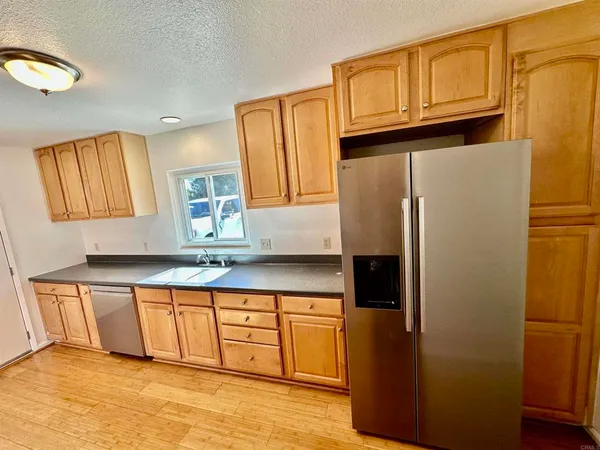a kitchen with granite countertop a refrigerator a sink and dishwasher