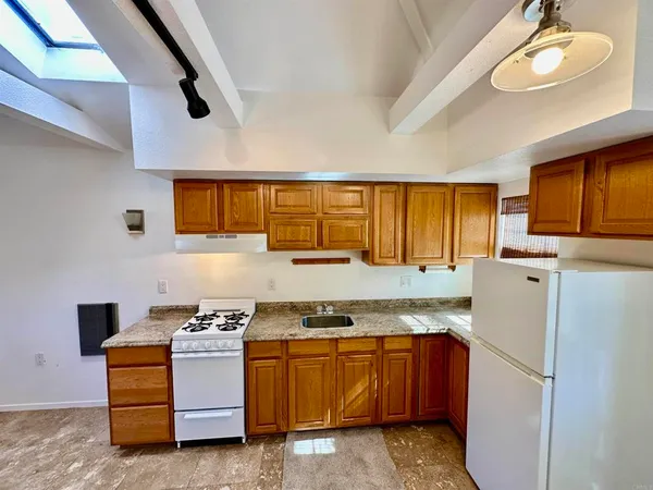 a kitchen with granite countertop a refrigerator and a stove