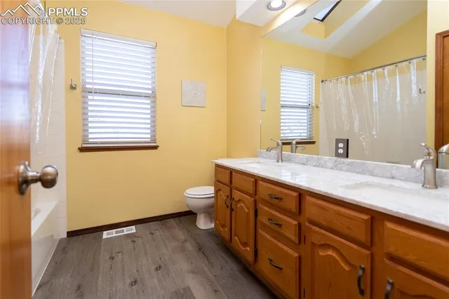 a bathroom with a granite countertop sink toilet and next to a window