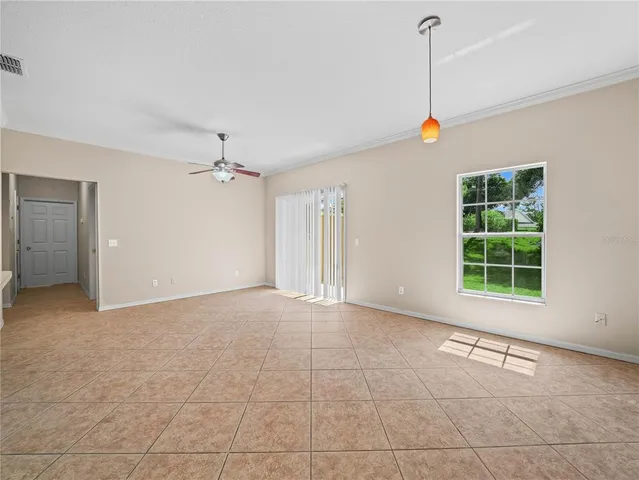 an empty room with wooden floor chandelier fan and windows