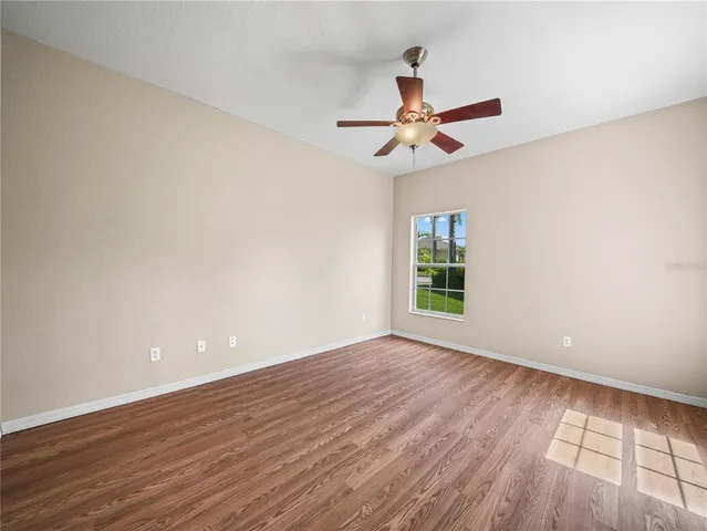 a view of an empty room with window and wooden floor