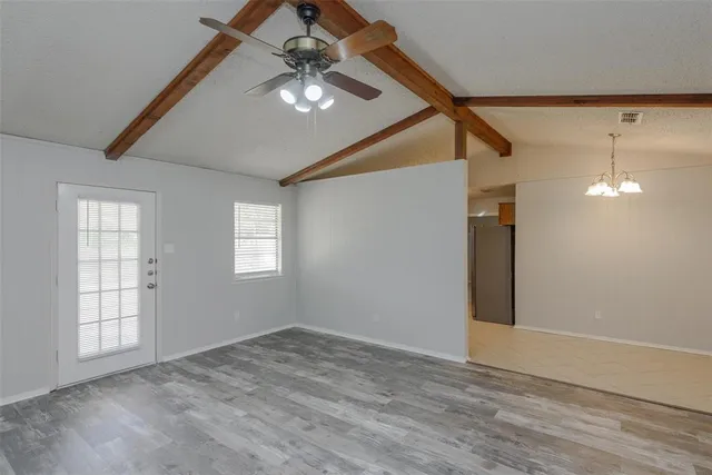 an empty room with wooden floor fan and windows