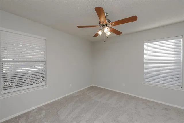 an empty room with a window and a fan