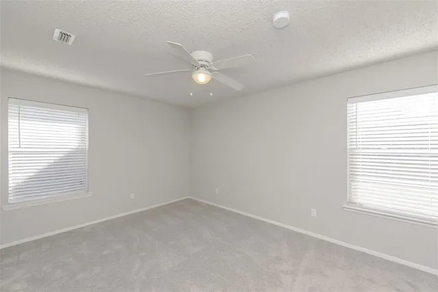 an empty room with a window and a fan