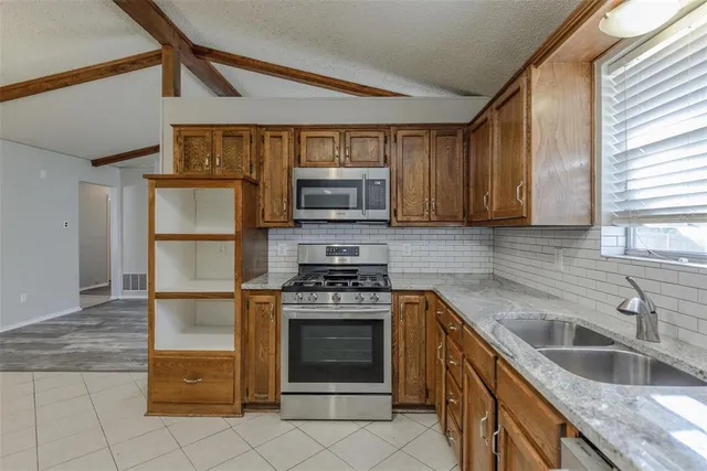 a kitchen with granite countertop a stove top oven and cabinets