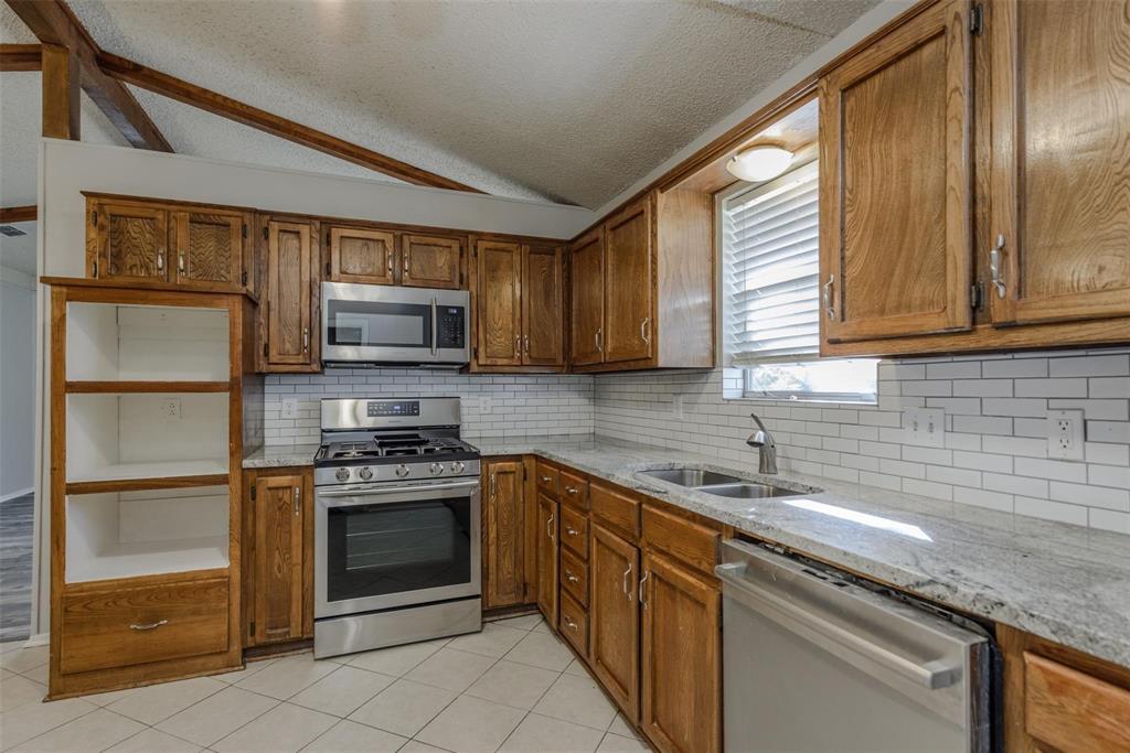 3609 Cooper Branch East Denton, TX 76209 - Photo 9 of 23 a kitchen with stainless steel appliances granite countertop a sink stove and microwave