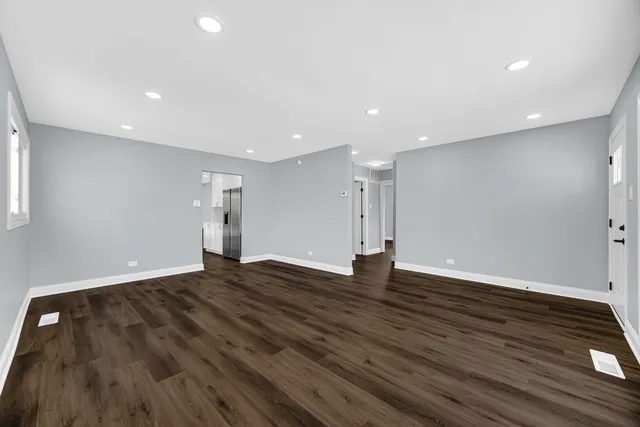 a view of an empty room with wooden floor and closet