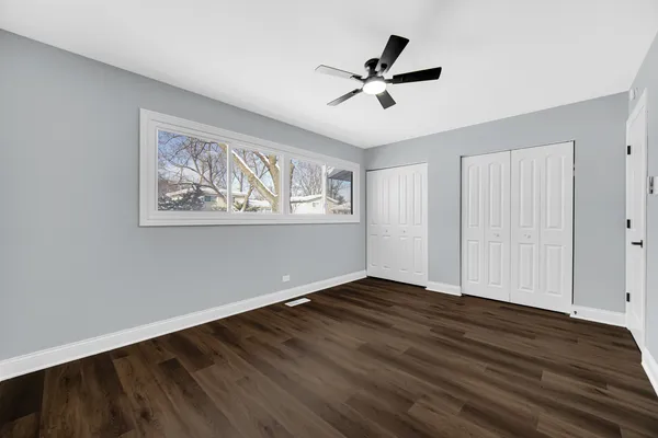 a view of empty room with wooden floor and fan