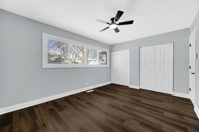a view of empty room with wooden floor and fan