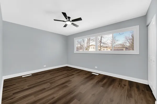 a view of empty room with wooden floor and fan