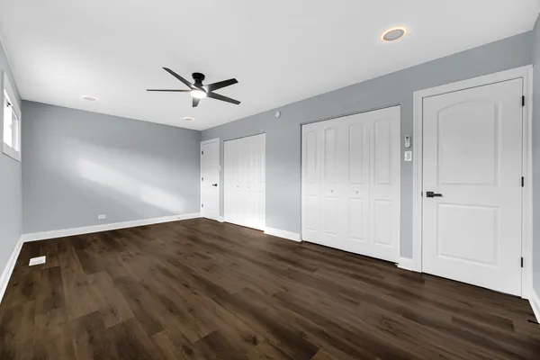 an empty room with wooden floor and ceiling fan
