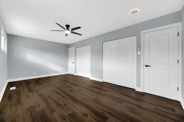 an empty room with wooden floor and ceiling fan