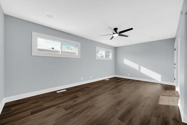 an empty room with wooden floor and ceiling fan