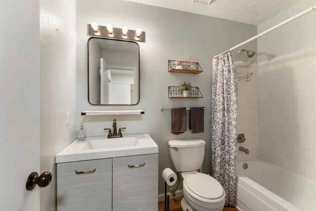a bathroom with a toilet sink vanity tub and shower