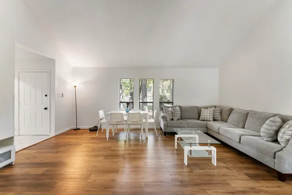 a living room with couches and kitchen view with wooden floor