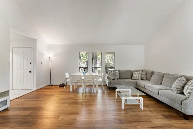 a living room with couches and kitchen view with wooden floor