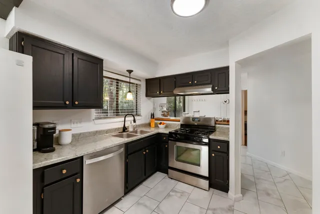 a kitchen with stainless steel appliances granite countertop a sink stove and refrigerator