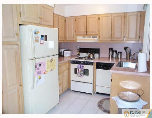 5 Rodney Road East Brunswick, NJ 08816 - Photo 4 of 8 a white kitchen with a stove a refrigerator and cabinets