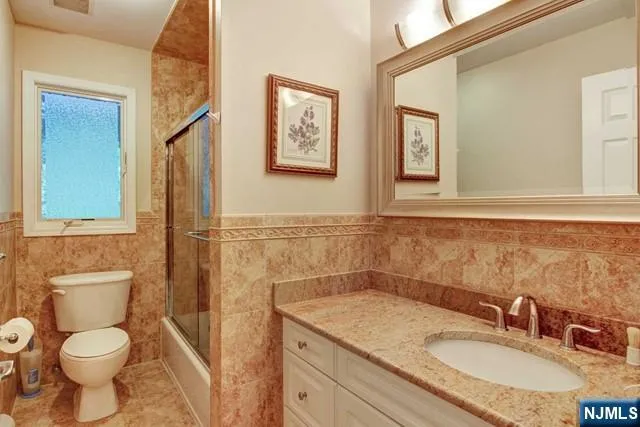 a bathroom with a granite countertop toilet sink and mirror
