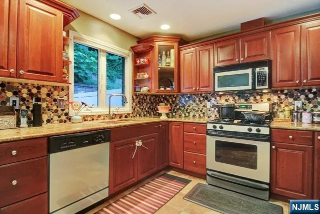a kitchen with stainless steel appliances granite countertop wooden cabinets a sink and a stove