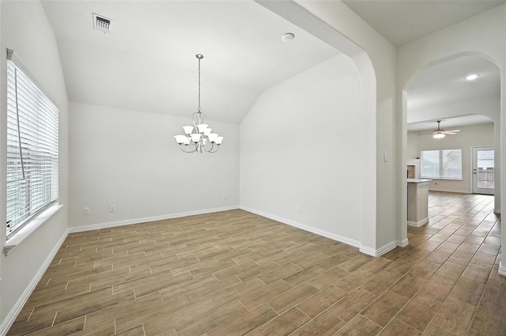 5 Pheasant Run Sanger, TX 76266 - Photo 4 of 27 Empty room with a ceiling fan, vaulted ceiling, light wood-style flooring, arched walkways, and a chandelier