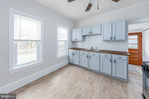 a kitchen with white cabinets and wooden floors