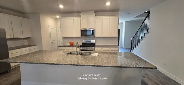 a kitchen with granite countertop a sink a stove and a wooden cabinets