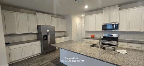 a kitchen with stainless steel appliances granite countertop a refrigerator a stove and a sink