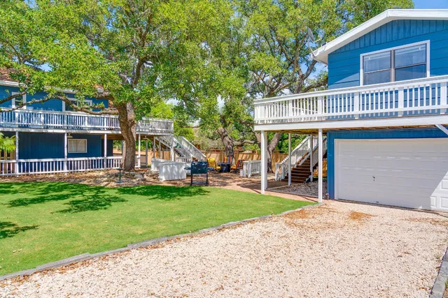 a view of a house with a yard deck and a large tree