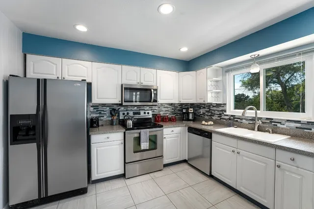 a kitchen with stainless steel appliances kitchen island granite countertop a refrigerator and a stove top oven