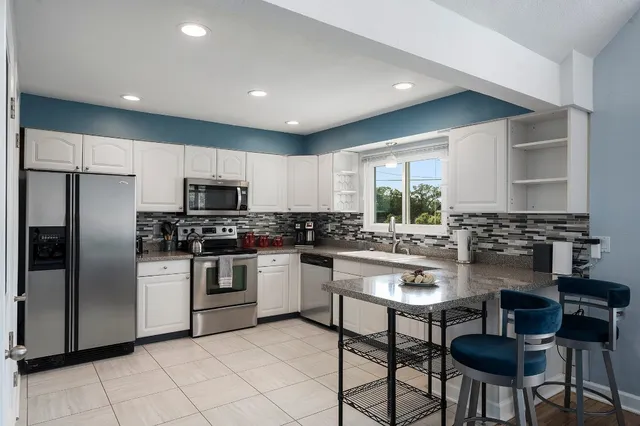 a dining room with furniture wooden floor and a kitchen view