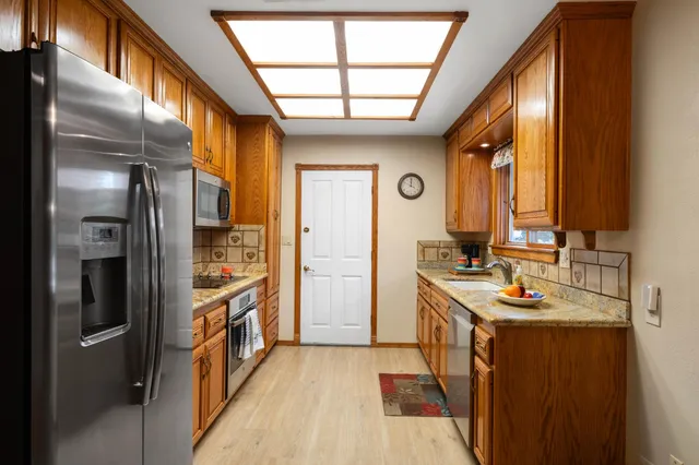 a kitchen with stainless steel appliances granite countertop a refrigerator a stove and a sink with large window