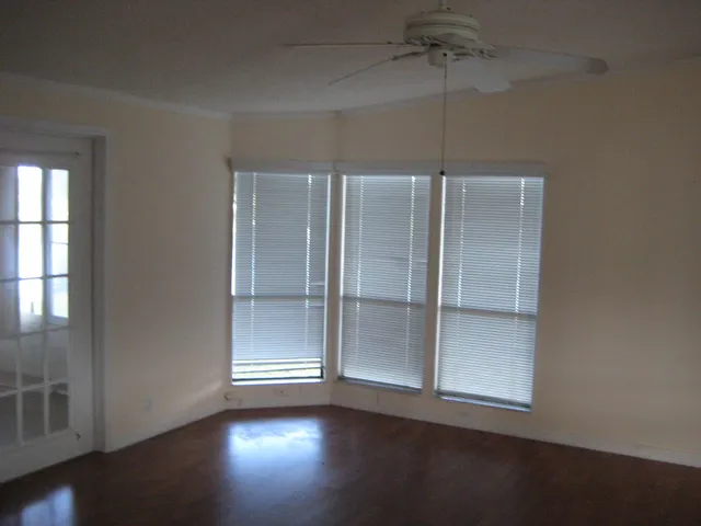 an empty room with wooden floor closet and windows