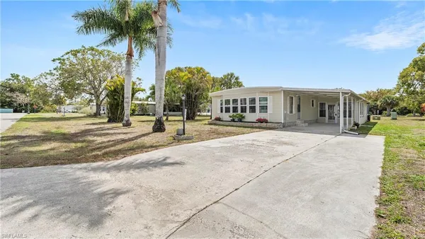 a view of a house with a yard and palm trees