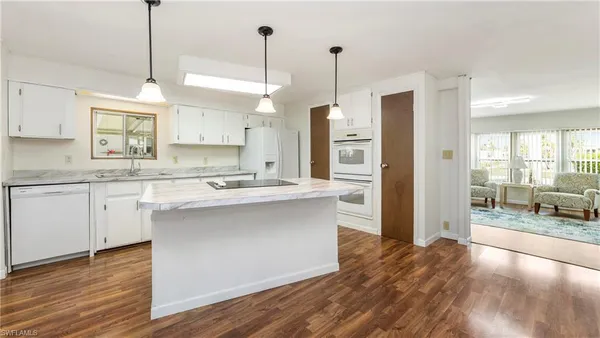 a kitchen with stainless steel appliances granite countertop a sink a refrigerator a stove and white cabinets with wooden floor