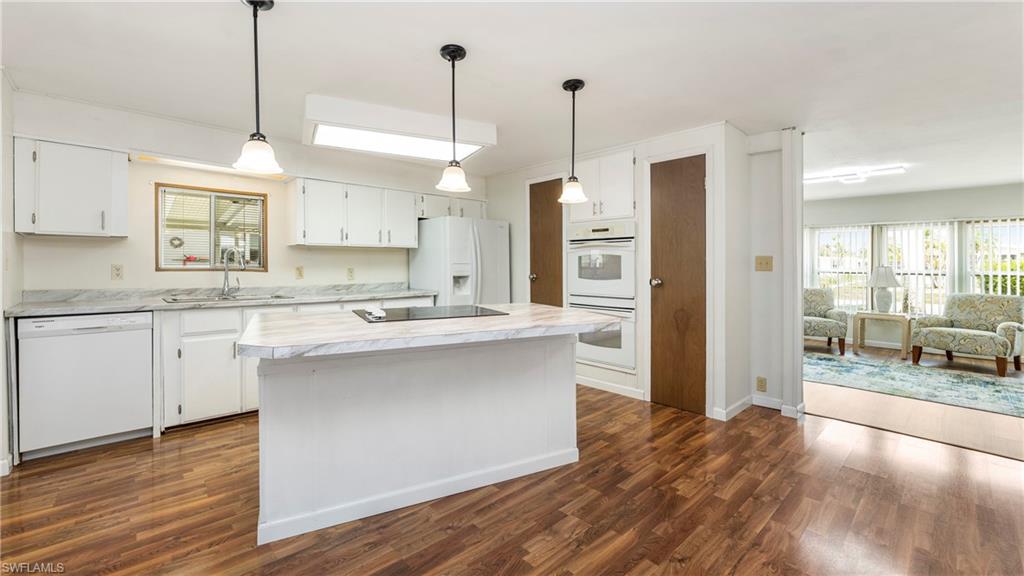 250 Indian Key Lane Naples, FL 34114 - Photo 7 of 33 a kitchen with stainless steel appliances granite countertop a sink a refrigerator a stove and white cabinets with wooden floor