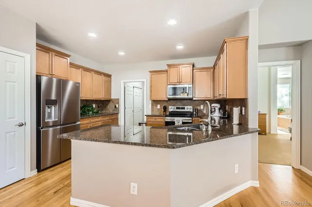 a kitchen with stainless steel appliances granite countertop a refrigerator a stove a sink and a refrigerator