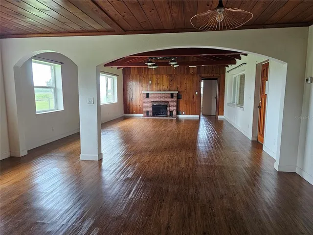 an empty room with wooden floor fireplace and windows