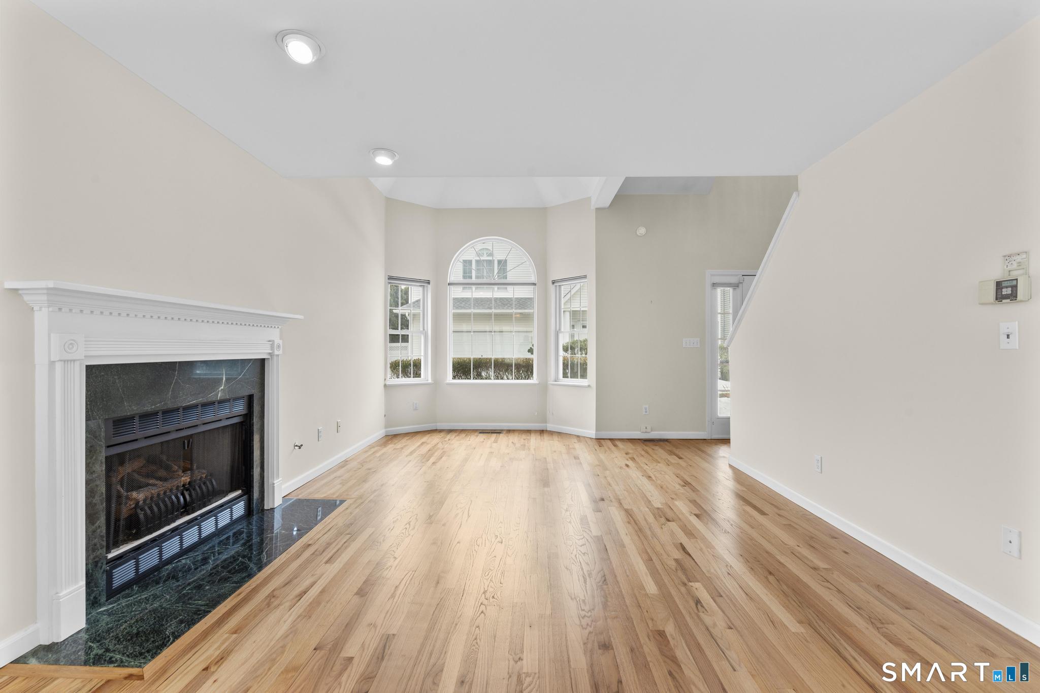 168 Colonial Road, Unit 6 Stamford, CT 06906 - Photo 12 of 41 an empty room with wooden floor fireplace and windows