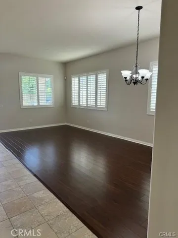 an empty room with wooden floor chandelier and windows